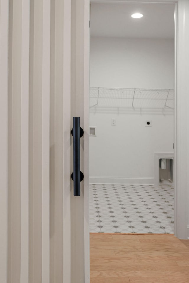 clothes washing area featuring electric dryer hookup and wood-type flooring