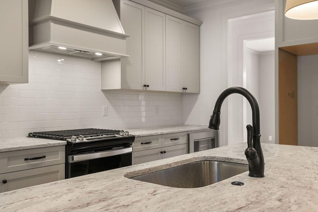 kitchen featuring premium range hood, backsplash, light stone countertops, and stainless steel stove