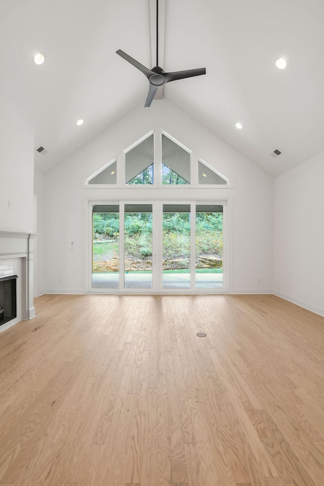 unfurnished living room featuring ceiling fan, light wood-type flooring, and vaulted ceiling