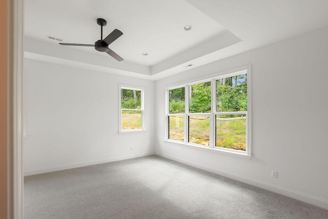 empty room featuring carpet, ceiling fan, and a tray ceiling