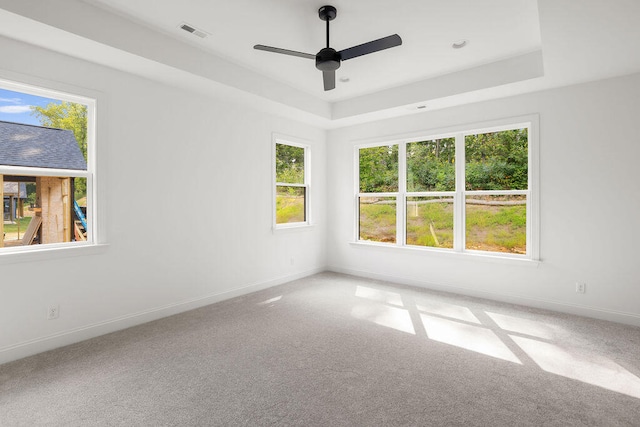 unfurnished room featuring ceiling fan, carpet floors, and a tray ceiling