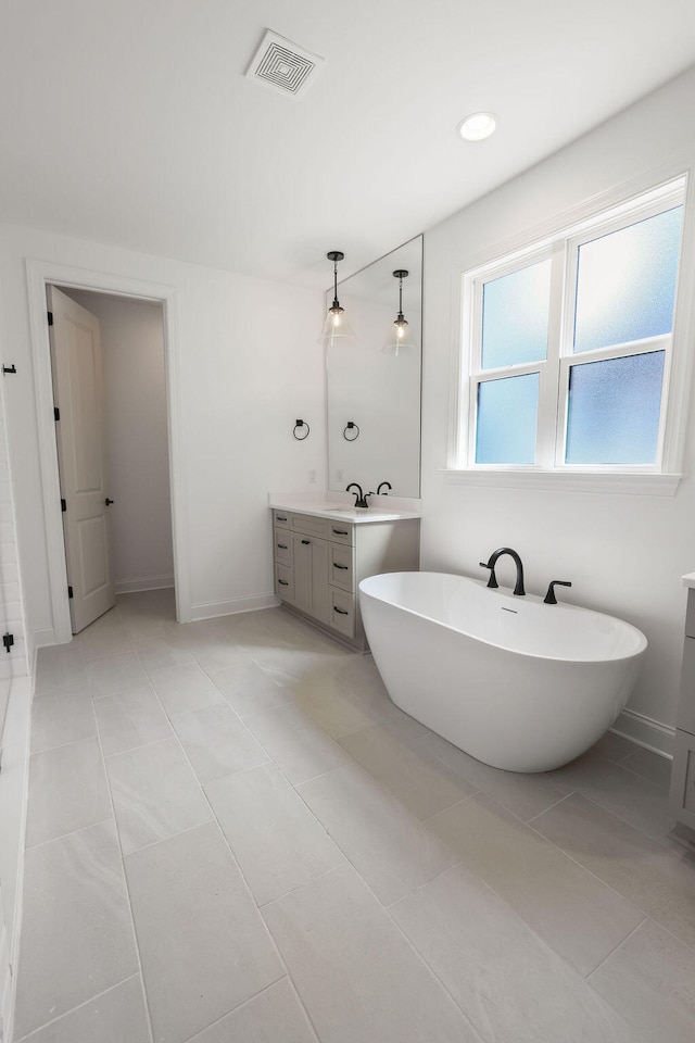 bathroom featuring tile patterned flooring, vanity, and a washtub