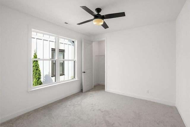 carpeted spare room featuring ceiling fan and a healthy amount of sunlight