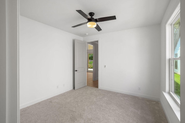 carpeted empty room with a wealth of natural light and ceiling fan