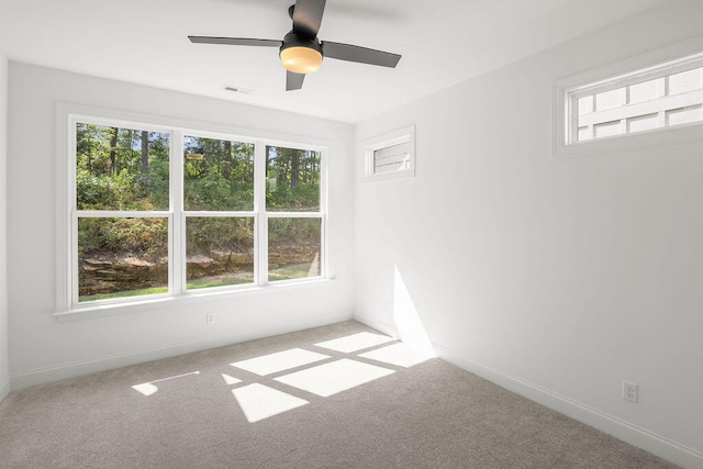 carpeted empty room with a wealth of natural light and ceiling fan