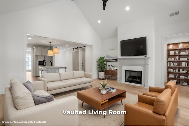 living room featuring a barn door, light hardwood / wood-style floors, and high vaulted ceiling