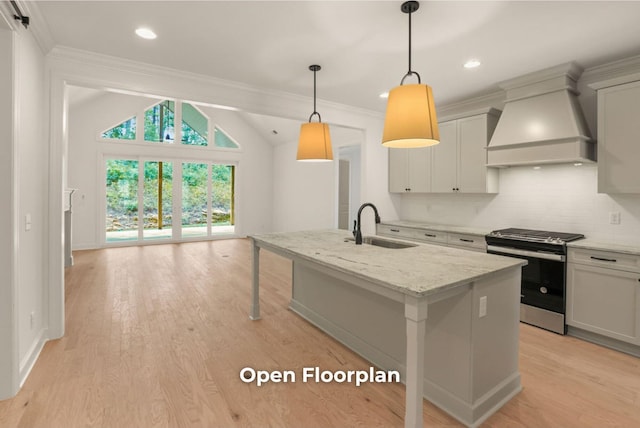 kitchen with light stone countertops, custom exhaust hood, sink, stainless steel range oven, and an island with sink