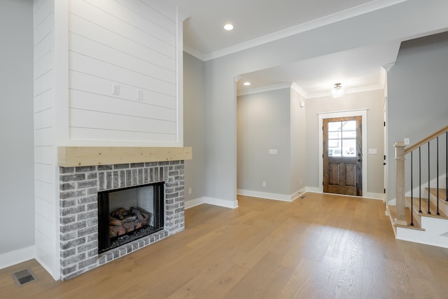 foyer entrance featuring light hardwood / wood-style floors, crown molding, and a fireplace