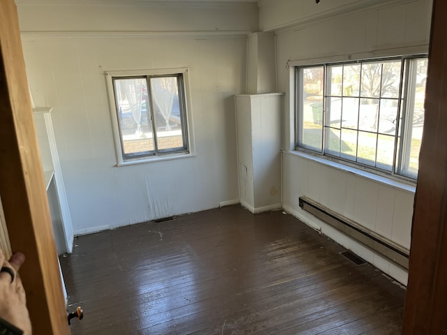 spare room featuring dark hardwood / wood-style flooring, a healthy amount of sunlight, and a baseboard radiator