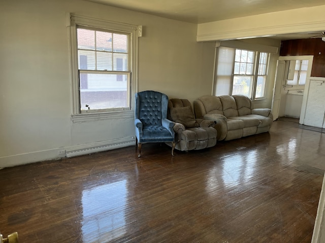 unfurnished living room featuring plenty of natural light, a baseboard heating unit, and dark hardwood / wood-style floors