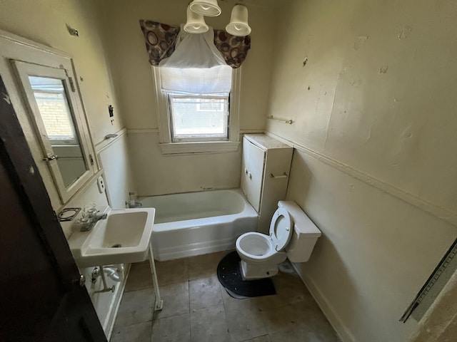 bathroom featuring toilet, a tub to relax in, and sink