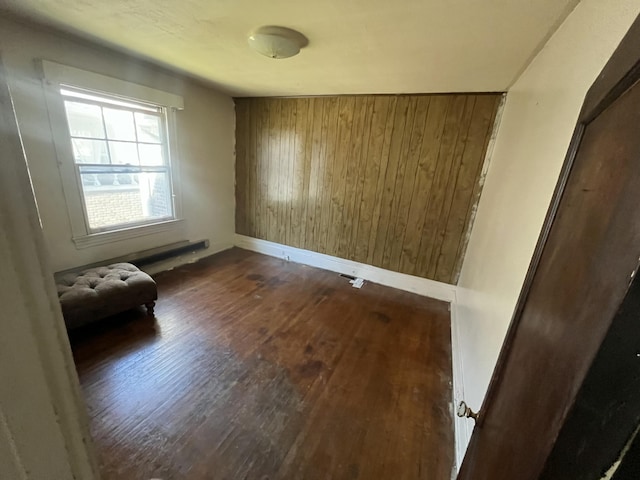 unfurnished room featuring dark hardwood / wood-style flooring and wooden walls