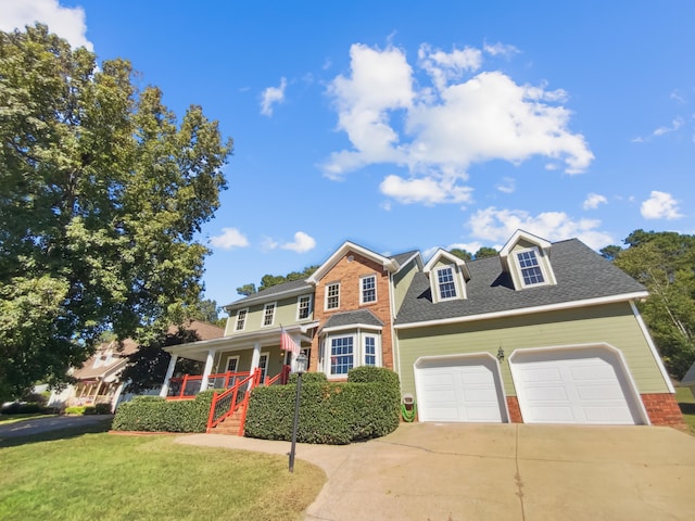 view of front of property with covered porch, a garage, and a front yard