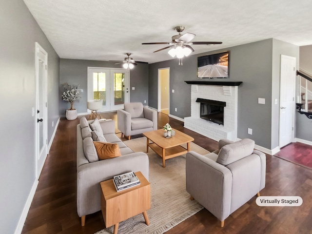 living room featuring ceiling fan, a fireplace, and dark hardwood / wood-style floors