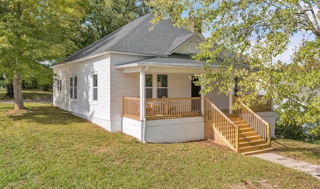 view of front of house with covered porch, roof with shingles, a front lawn, and stairway