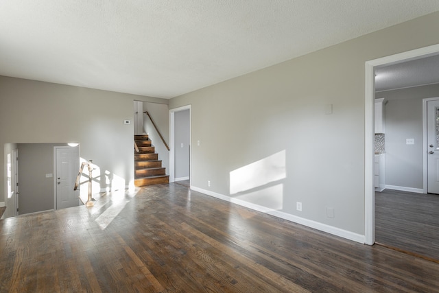 unfurnished living room featuring dark wood-type flooring and a textured ceiling