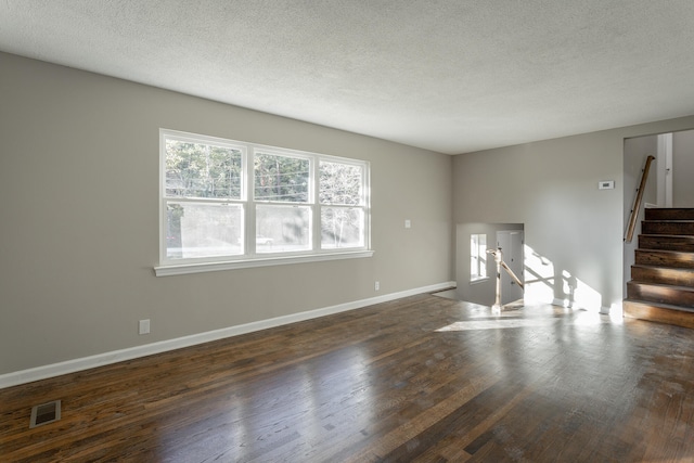 empty room with a textured ceiling and dark hardwood / wood-style floors