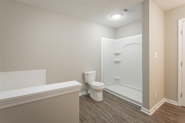 bathroom with a textured ceiling, a shower, wood-type flooring, and toilet