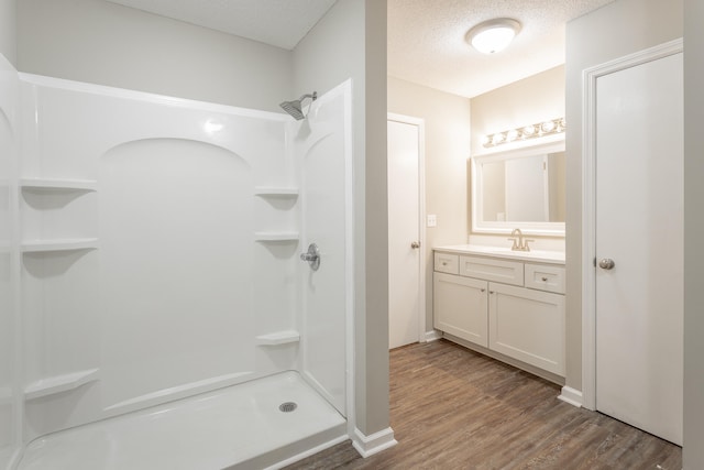 bathroom featuring vanity, walk in shower, a textured ceiling, and hardwood / wood-style floors