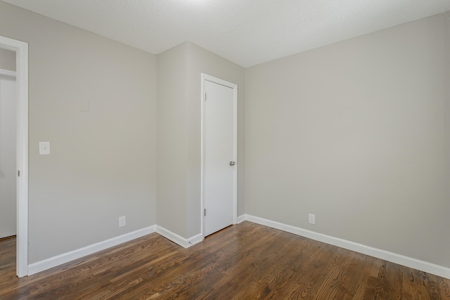 unfurnished bedroom featuring a textured ceiling and dark hardwood / wood-style flooring