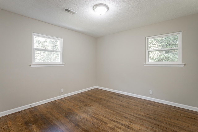 unfurnished room with a textured ceiling, a wealth of natural light, and dark hardwood / wood-style floors