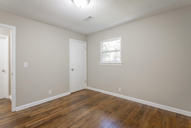 empty room with a textured ceiling and dark hardwood / wood-style flooring