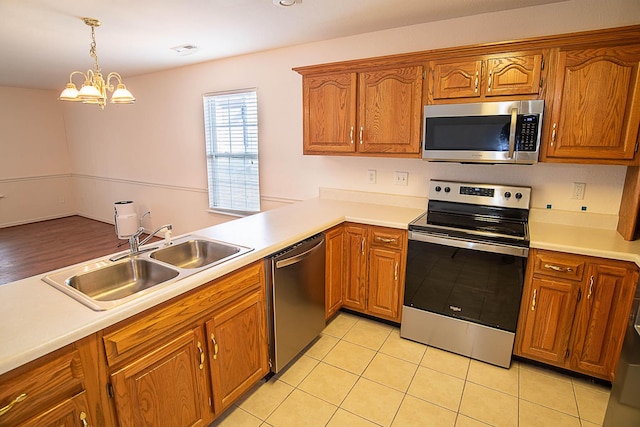 kitchen featuring an inviting chandelier, sink, hanging light fixtures, kitchen peninsula, and stainless steel appliances