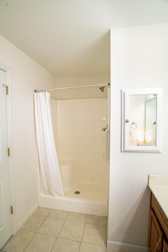 bathroom with tile patterned flooring, a textured ceiling, vanity, and curtained shower