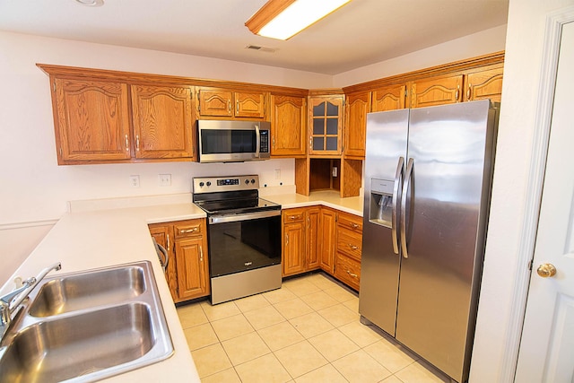 kitchen with sink, light tile patterned flooring, and appliances with stainless steel finishes