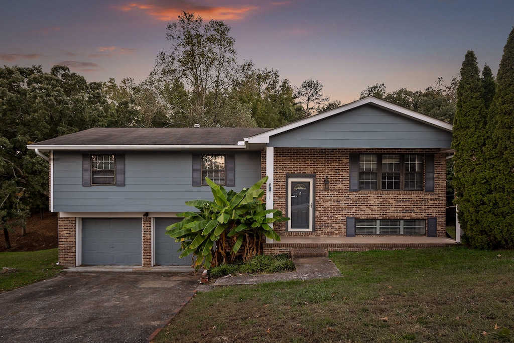 raised ranch featuring a yard and a garage