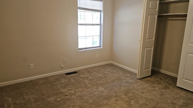 unfurnished bedroom with dark carpet and a closet