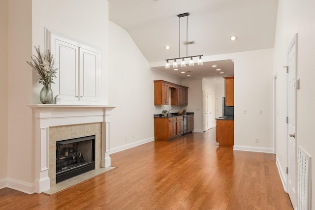 unfurnished living room featuring lofted ceiling, sink, a fireplace, and wood-type flooring