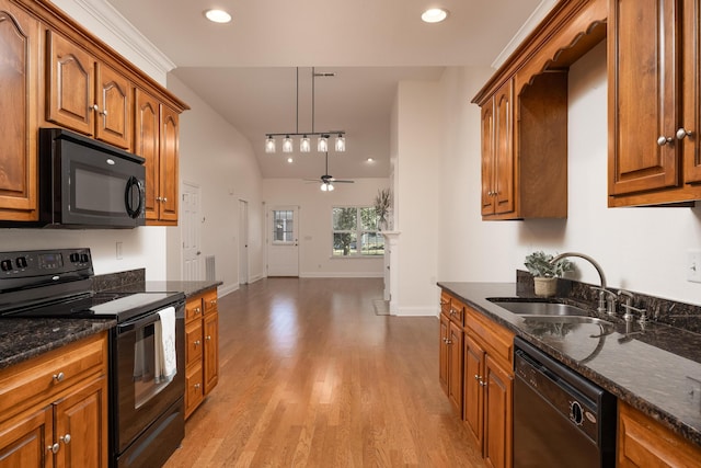 kitchen featuring black appliances, sink, light wood-type flooring, hanging light fixtures, and lofted ceiling