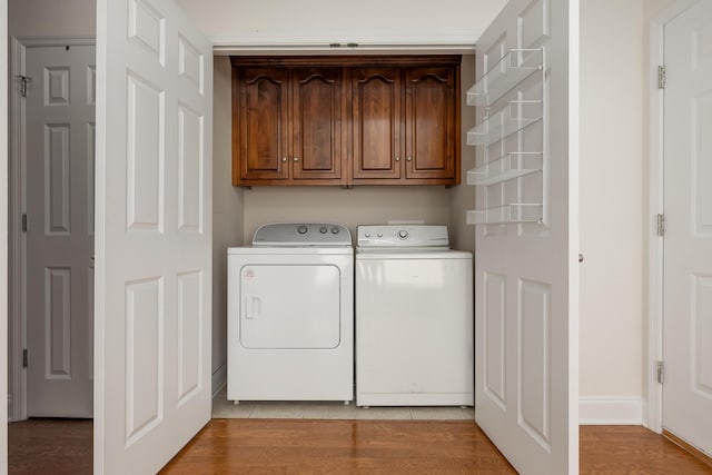 laundry room featuring cabinets, hardwood / wood-style floors, and washing machine and clothes dryer