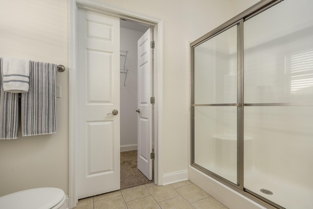 bathroom featuring toilet, walk in shower, and tile patterned flooring