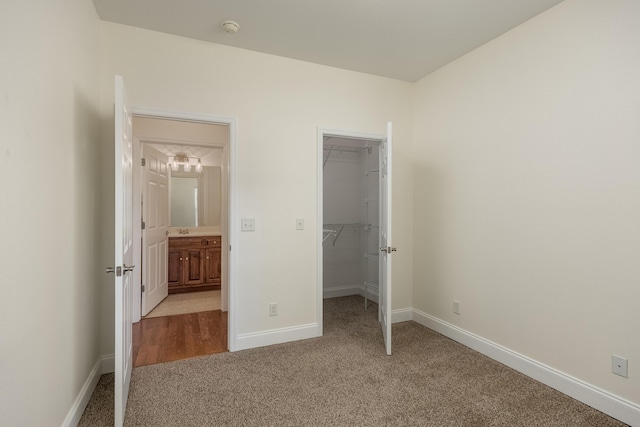 unfurnished bedroom with a walk in closet, a closet, and light colored carpet