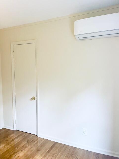 unfurnished room with a wall mounted AC and hardwood / wood-style floors