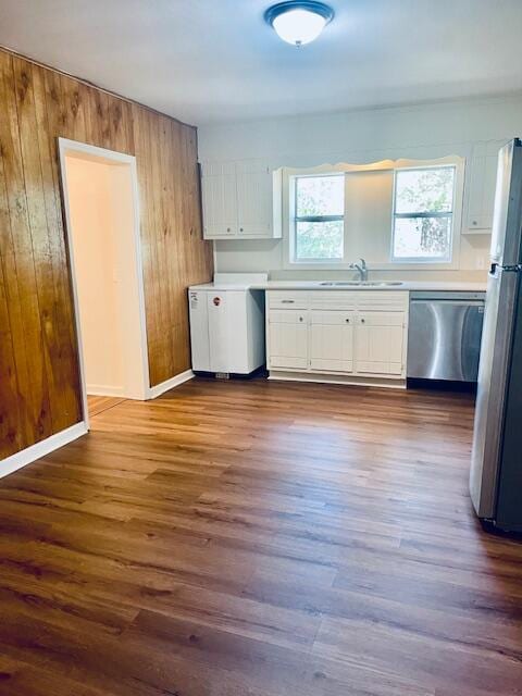 kitchen featuring wood walls, white cabinetry, stainless steel appliances, and dark hardwood / wood-style flooring