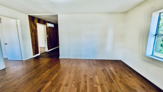 unfurnished room featuring an AC wall unit, dark hardwood / wood-style floors, and plenty of natural light