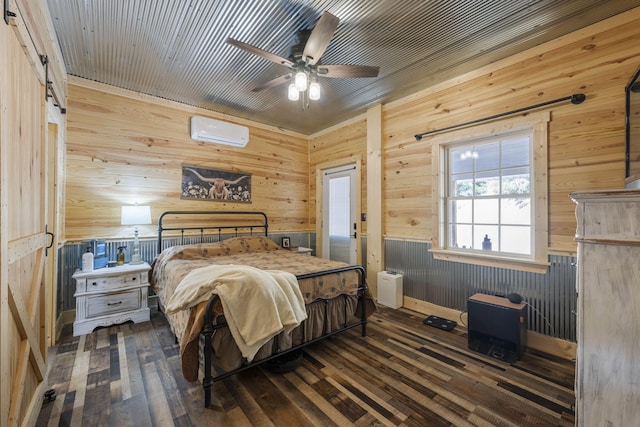 bedroom with wood walls, a wall mounted air conditioner, a barn door, dark hardwood / wood-style flooring, and ceiling fan