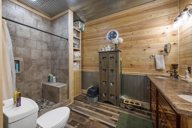 bathroom with toilet, wooden walls, wood-type flooring, curtained shower, and vanity