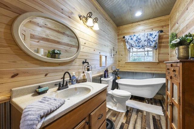 bathroom with vanity, wooden walls, toilet, and a bath