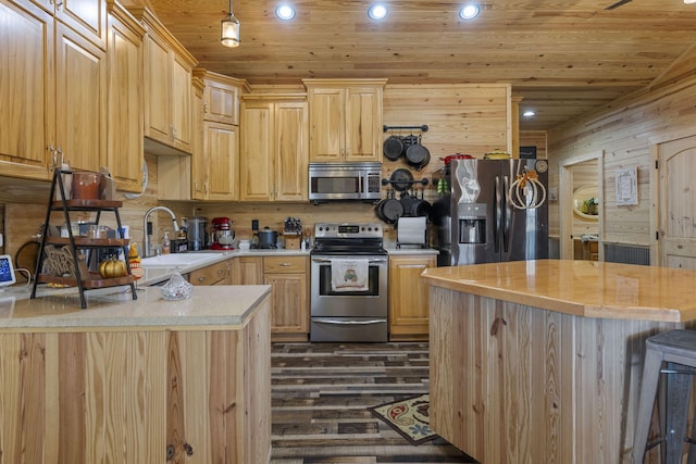 kitchen featuring dark wood-type flooring, wooden walls, sink, light brown cabinetry, and appliances with stainless steel finishes