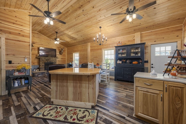 kitchen with a kitchen island, wood ceiling, dark wood-type flooring, wooden walls, and a fireplace