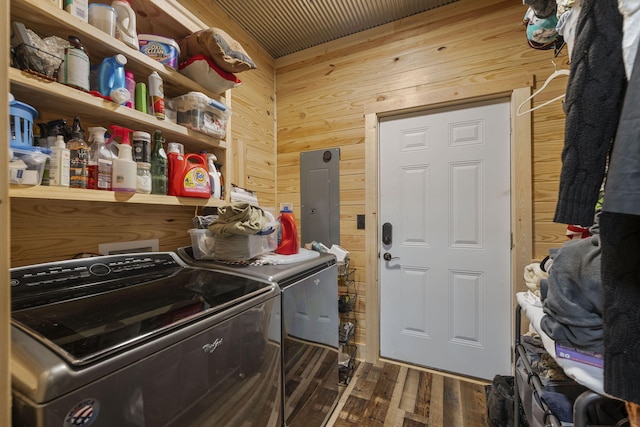 laundry area featuring wood walls, electric panel, washing machine and dryer, and dark hardwood / wood-style flooring