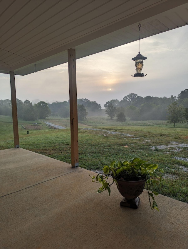 patio terrace at dusk featuring a rural view