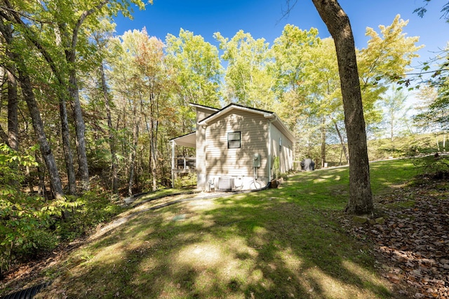 view of side of home featuring central air condition unit and a yard