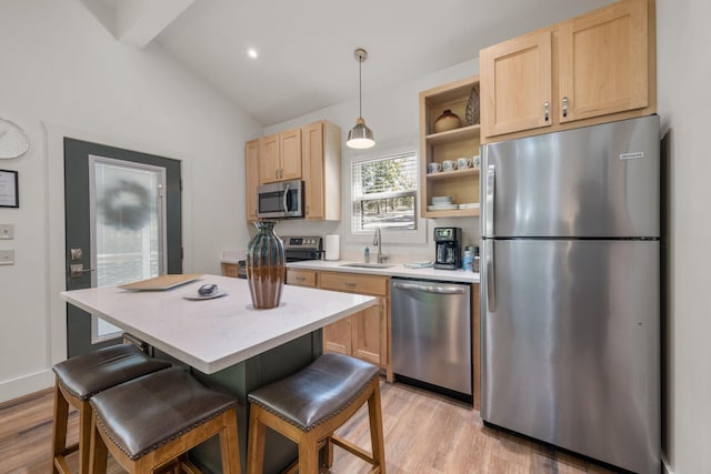 kitchen featuring light brown cabinets, stainless steel appliances, hanging light fixtures, and light countertops