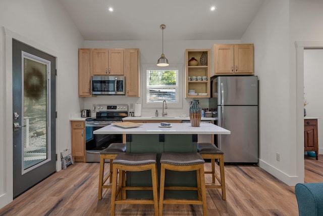 kitchen with light countertops, appliances with stainless steel finishes, hanging light fixtures, and a kitchen breakfast bar