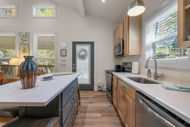 kitchen featuring light stone countertops, sink, a center island, stainless steel appliances, and pendant lighting